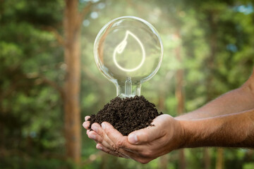 Hands holding soil with light bulb. Sustainable and eco friendly energy sources. Earth energy concept.