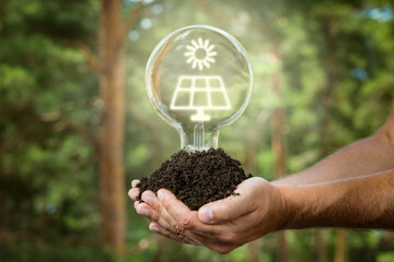 Fototapeta na wymiar Hands holding soil with light bulb. Sustainable and eco friendly energy sources. Earth energy concept.