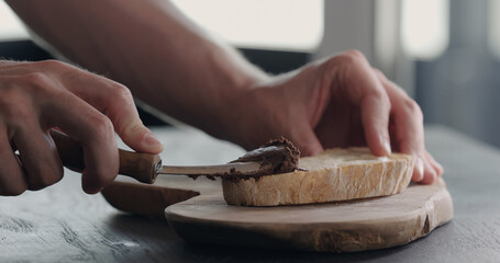 man spread chocolate hazelnut butter on rustic bread
