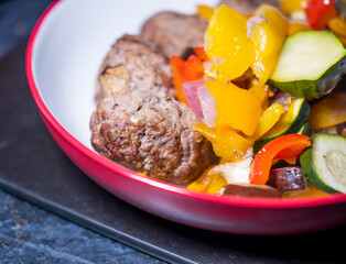 A bowl of homemade kofte meatballs and oven baked or roasted Mediterranean vegetables