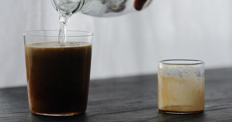 making espresso tonic pour tonic in espresso on black wood table