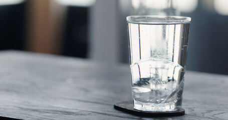 tonic water with clear ice ball in tumbler glass on black oak table