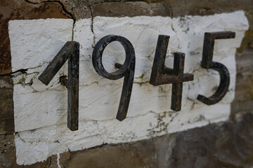 1945, Gußeiserne Zahlen vor weißem Hintergrund einer Bruchsteinwand