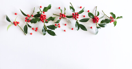 Christmas decoration with holly leaves and berries, isolated on white background. Top view. Winter...