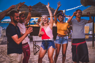 Group of happy multiracial friends dancing at sunset beach party in summer vacation - Young...