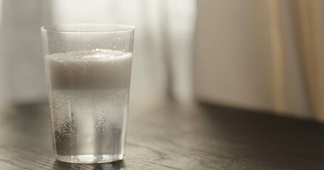 pour sparkling water in tumbler glass on black oak table with copy space