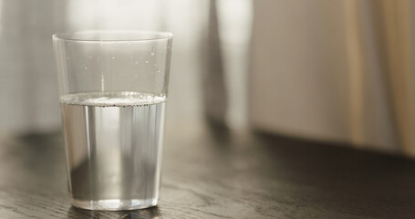 sparkling water in tumbler glass on black oak table with copy space