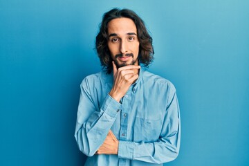 Young hispanic man wearing casual clothes with hand on chin thinking about question, pensive expression. smiling with thoughtful face. doubt concept.