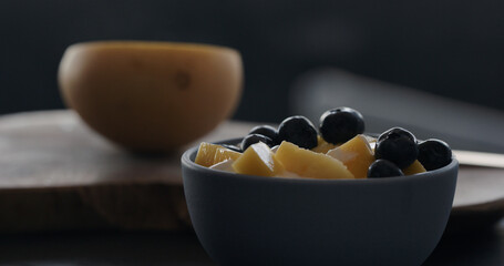 put fresh blueberries over thai mango in natural organic yogurt in blue bowl