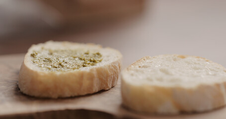 pesto on fresh baguette slice to make sandwich closeup