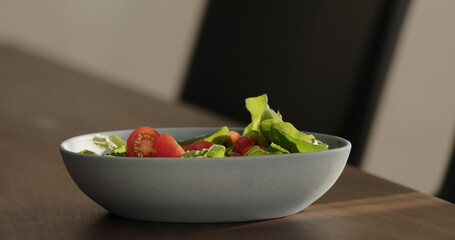 pour oil in blue bowl on walnut table making salad