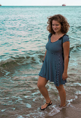 Fototapeta na wymiar A girl walks along the wet sand along the sea