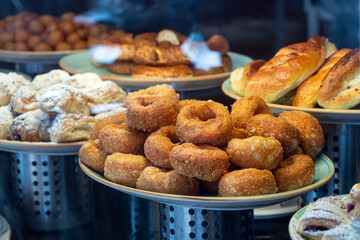 a plate of fried crispy donuts, a showcase in a bakery with pastries