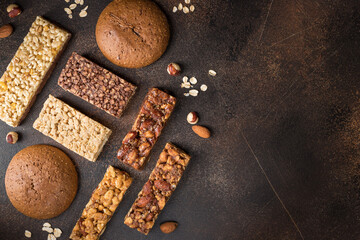 Different energy protein bars on dark background. Healthy granola superfood bars. copy space