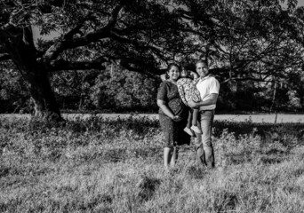 Pregnant mother, father and toddler daughter spending time outdoors. Happy maternity scene of...