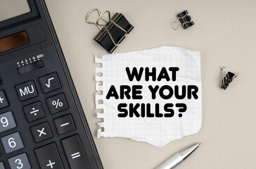 On the table is a calculator, a pen and paper with the inscription - What Are Your Skills