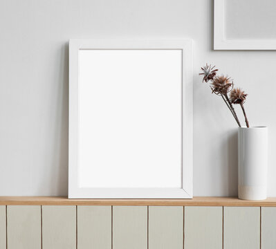 Blank picture frame mockup on white wall. White living room design. View of modern scandinavian style interior with artwork mock up on wall. Home staging and minimalism concept