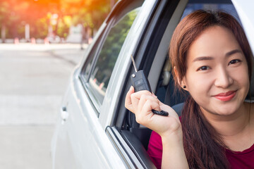 pretty smiling asian female driver in car showing her car key