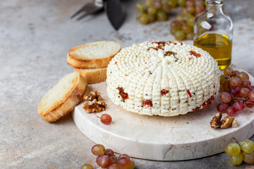 round homemade cheese with herbs and dried tomatoes