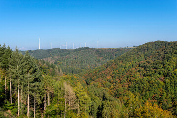 Obraz premium Wind turbines for electricity production over a dense forest in western Germany.