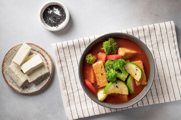 Tomato soup with tofu cheese, broccoli and zucchini in bowl. vegan food concept. top view