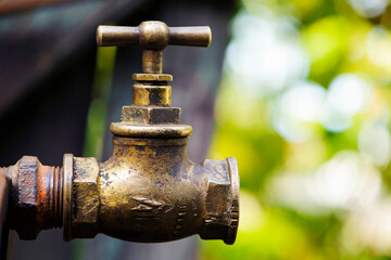 old brass water tap isolated on a light background. tap valve. old copper retro faucet on a rusty pipe. plumbing, repair, dismantling. Vintage close-up. outdoor water tap