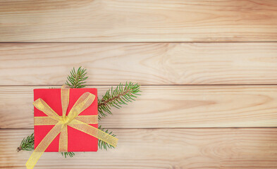 Christmas wooden background with red gift box and Christmas tree branch	
