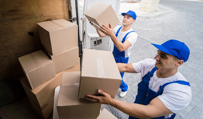 Two removal company workers unloading boxes from minibus