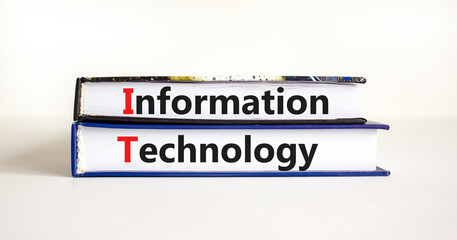 IT, information technology symbol. Concept words 'IT, information technology' on books on a beautiful white table, white background. Business, IT, information technology concept, copy space.