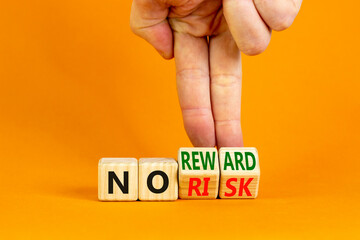 No risk or reward symbol. Businessman turns wooden cubes and changes words 'no risk' to 'no reward'. Beautiful orange background. No risk or reward and business concept. Copy space.