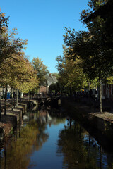 Fototapeta na wymiar Fall season in a city. Autumn trees, buildings on canal, colorful water reflections. Autumn in the Netherlands. 