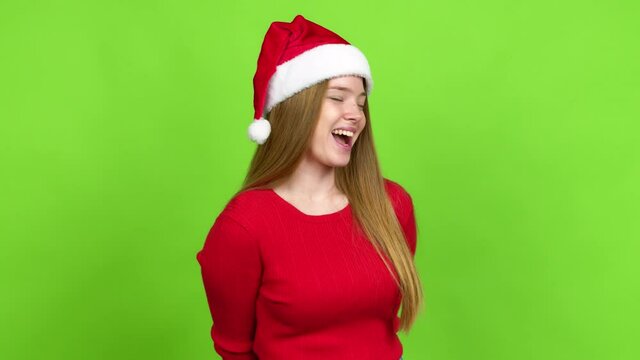 Teenager girl with christmas hat smiling a lot while covering mouth over isolated background. Green screen chroma key