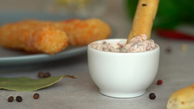 Bread stick dips in mayonnaise sauce with greens and spices. Toast crouton snack. Food background.
