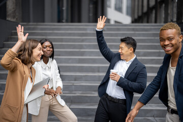 Asian businessman and caucasian businesswoman giving five each other on city street. Concept of modern successful business people. Idea of business cooperation. Joyful multiracial businessteam