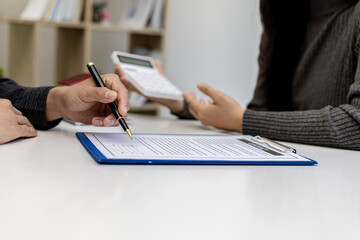 Real estate contract agreement concept. Buyer is signing house purchase contract with seller. Salesperson calculates house purchase cost and explains details on contract.