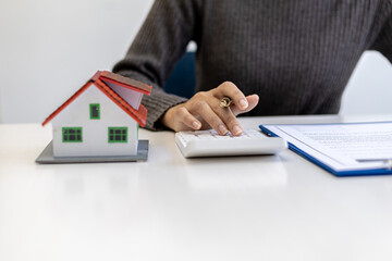 Fototapeta premium Businessman presses a calculator to calculate the amount on a housing estate sales document, he is meeting with the sales manager to place a sale and make promotions, marketing plans to increase sales