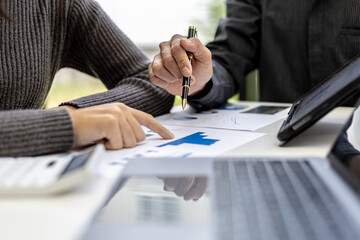 Close-up photo of two businessmen pointing at a sales data sheet in graph format, they are meeting together on the topic of managing sales growth. Concept of business cooperation and sales management.