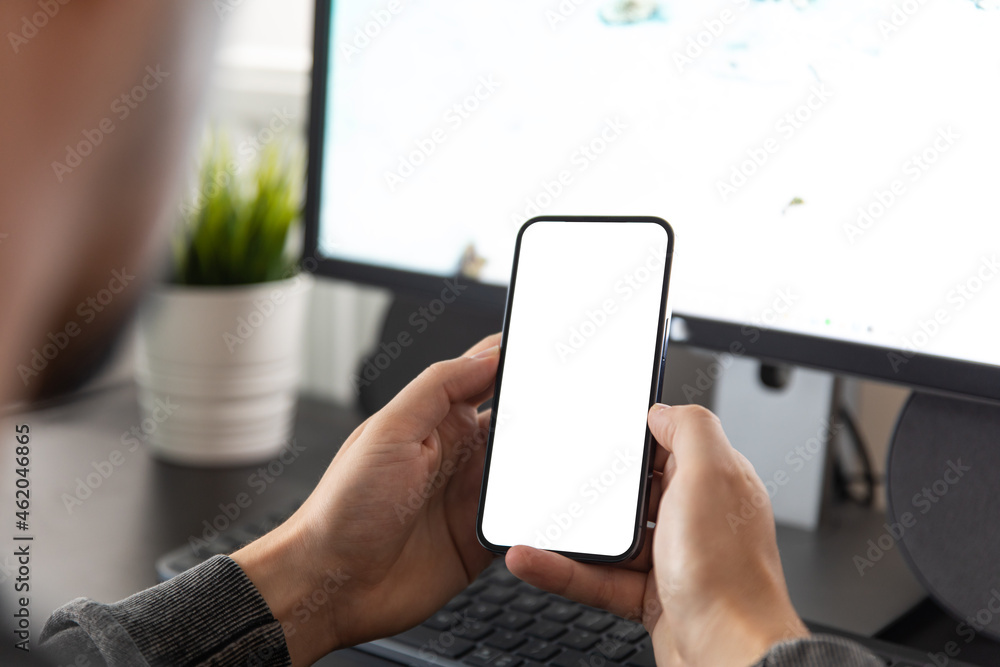 Aufkleber man using smartphone blank screen frameless modern design while sitting in front of the computer in 