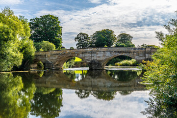 Fototapeta na wymiar A view of an old medieval bridge over the River Ure on the outskirts of Ripon, Yorkshire, UK in summertime