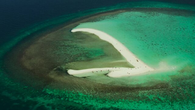 Tropical white island and sandy beach with tourists surrounded by coral reef and blue sea, aerial view. Sandbar Atoll. Island with sand bar and coral reef. Summer and travel vacation concept, Camiguin