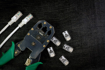 Modular plug crimper for RJ-45 with transparent connectors and ethernet cable on black wooden...