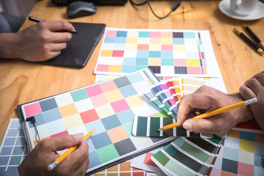 Interior designer chooses a color chart for home design. Graphic designers working on color chart at modern office.