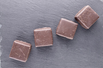Several sweet chocolates on a slate stone, close-up, top view.
