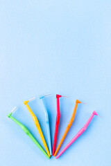 Different size interdental brush angles on blue background, vertical, copy space