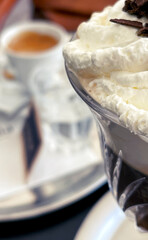 Close-up of a glass Irish Coffee with an espresso cup and white china in the background