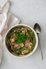 Fried brown champignons mushrooms with green beans in a creamy sauce with green onions and parsley, top view