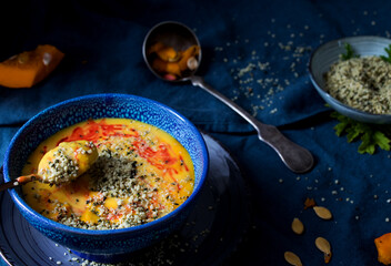 cremige kürbissuppe mit granatapfelsaft und Hanfsamen in einer blauen schüssel