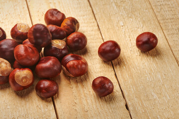 Heap of horse chestnuts on wooden table. Autumn nature harvest. Top view with copy space.