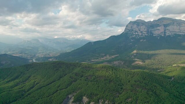 A great mountain, a rock protruding on a plateau in the Pyrenees mountains. Spectacular view of the mountain range from a drone with huge cumulus clouds in the background.