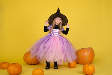 Funny child girl in witch costume for Halloween with pumpkin
